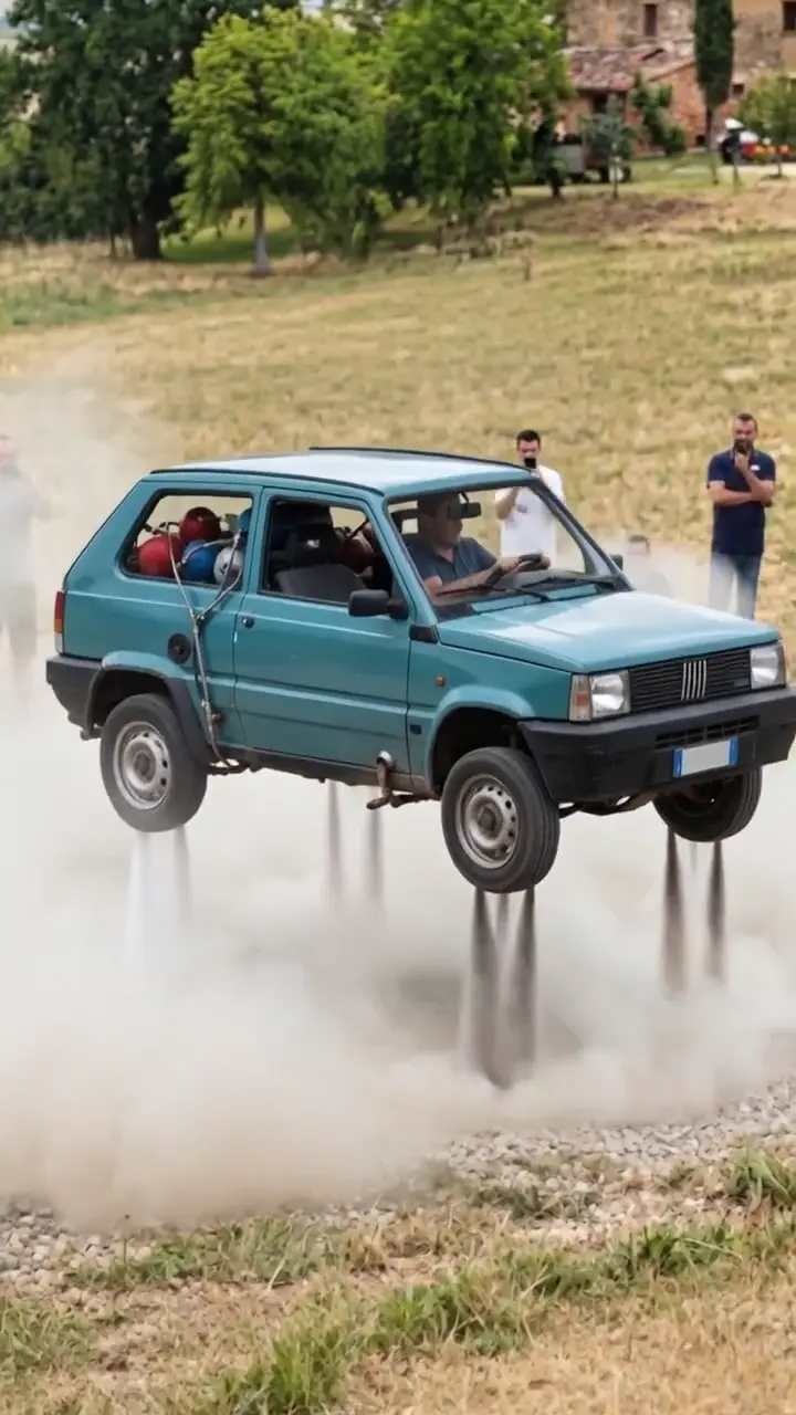 A green hatchback rises off a gravel road on four jets, hangs in a cloud of dust and drops back onto its wheels as a crowd films.